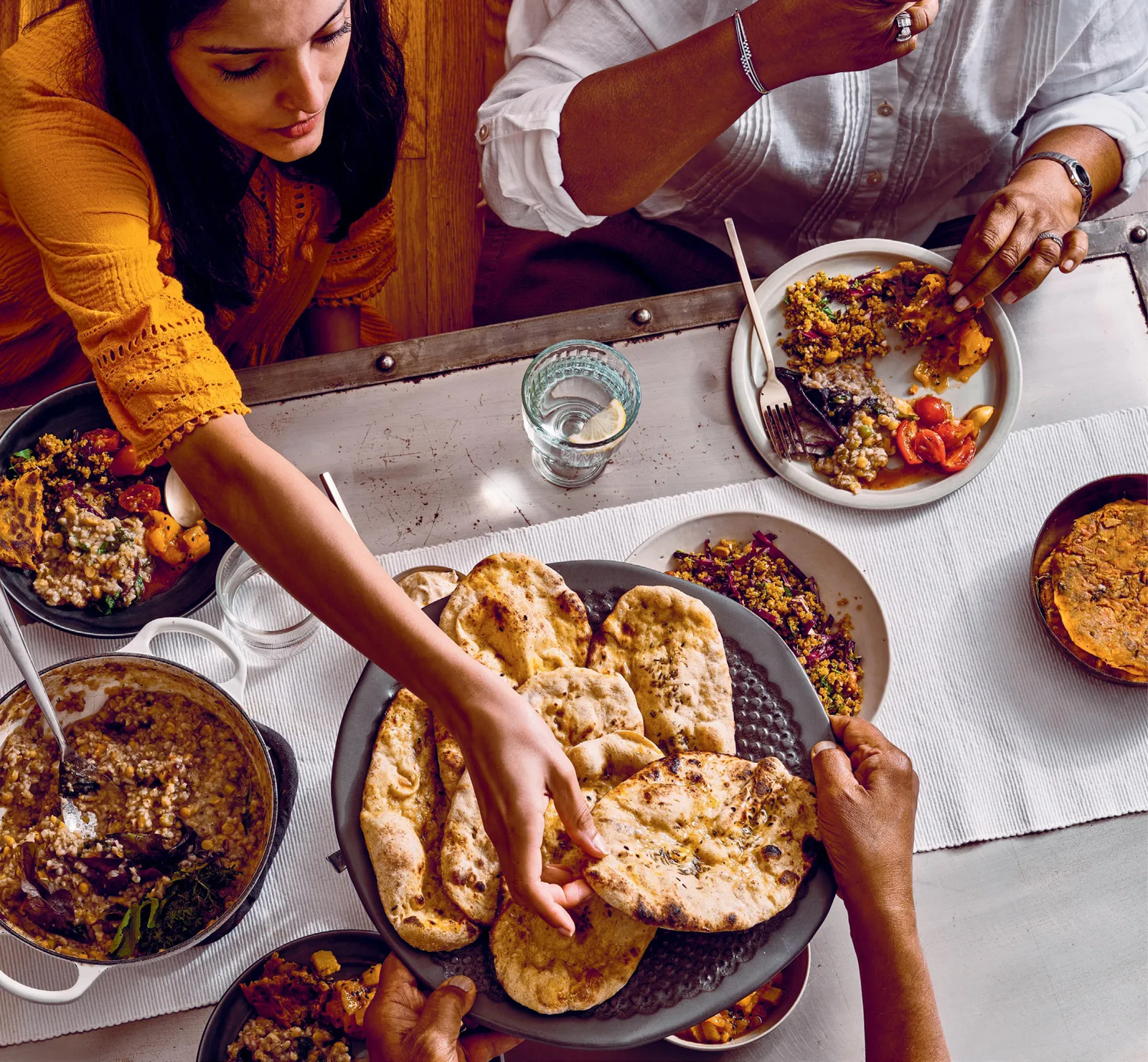 Stock photograph of Indian dishes and naan shared around a table