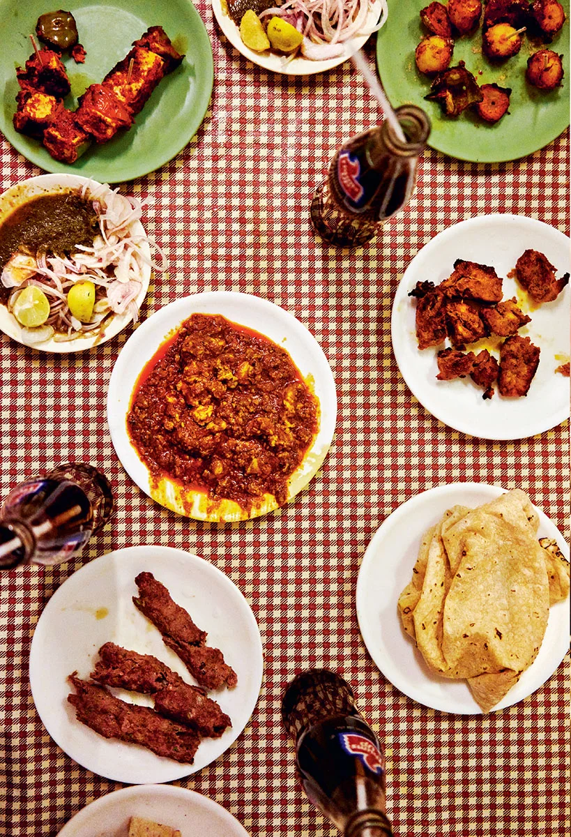 Indian grilled dishes, curry and flatbread arranged across a checked table